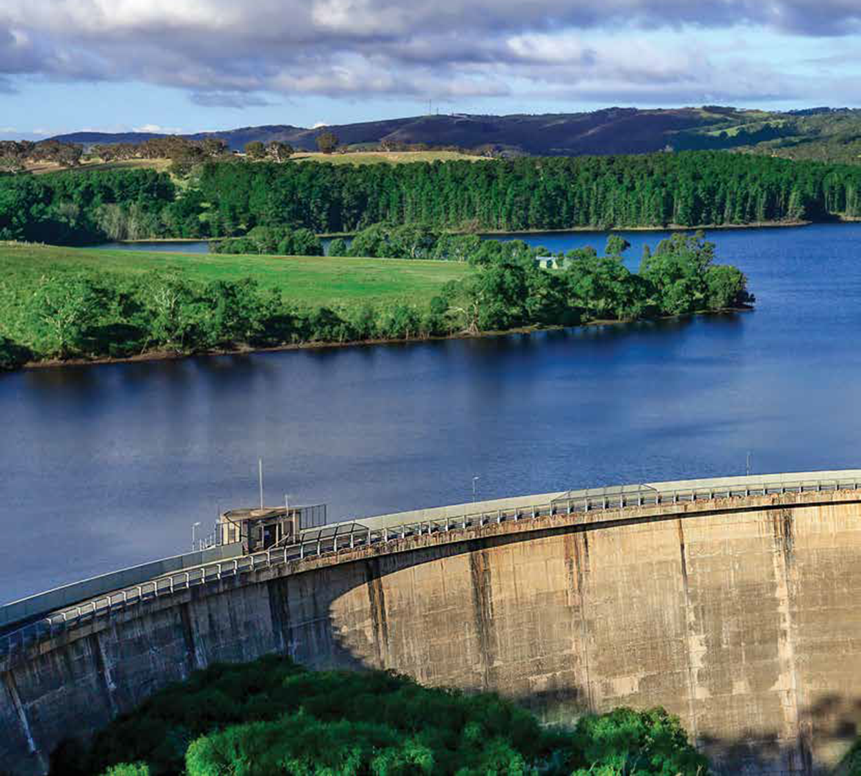 A large dam separating a large expanse of water by some green fields